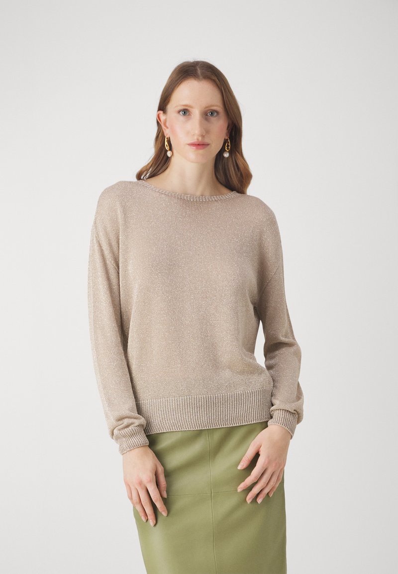 Pull en tricot pailleté beige clair avec des manches longues, un col rond et des poignets côtelés, associé à une jupe crayon verte.