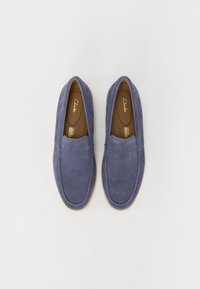 Tengerés kék velúr slip-on cipők lekerekített orral és sík krém színű talppal, varrott részletekkel és perforált belső béléssel.