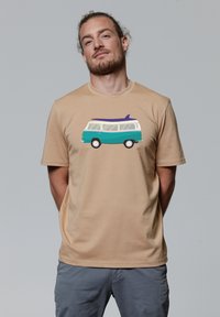 Beige t-shirt met een grafisch ontwerp van een teal en witte retro bus met een surfplank op het dak. Zachte katoen, korte mouwen, relaxte pasvorm.