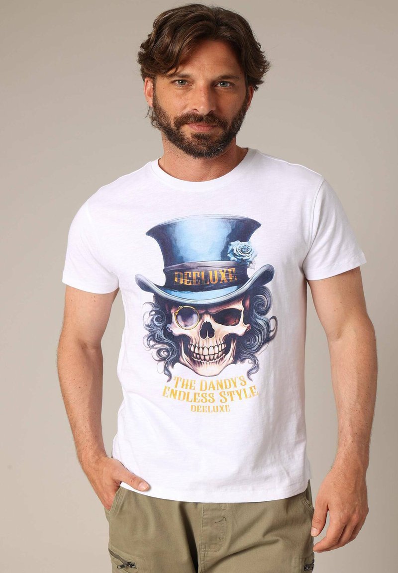 Witte katoenen t-shirt met een grafische print van een schedel met een hoge hoed, gouden accenten en de tekst "DE EINDLOZE STIJL VAN DE DANDY."