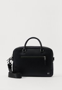 Sac en cuir noir texturé avec doubles poignées et une bandoulière amovible. Comprend une poche zippée à l'avant et un logo en relief.