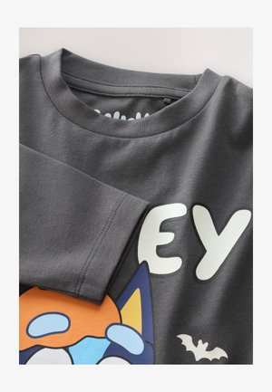 Szary bawełniany t-shirt z kolorowym, kreskówkowym nadrukiem przedstawiającym pomarańczową postać, duże białe litery oraz mały obrazek nietoperza.