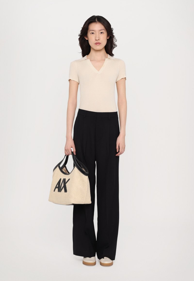 Knit beige polo top, black wide-leg trousers, and a cream bag with black accents and “AX” logo. Smooth textures and fitted design.