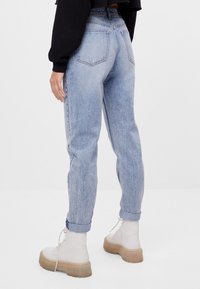 Ljusblå högmidjade jeans med en avslappnad passform, uppvikta fållar och femficksdesign. Kombination med kraftiga vita plattformsskor.