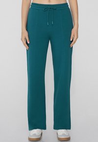 Teal Jogginghosen mit lockerer Passform, elastischem Taillenzug und Kordelzug. Glatte Textur, gerade Beine und Seitennaht für Struktur.