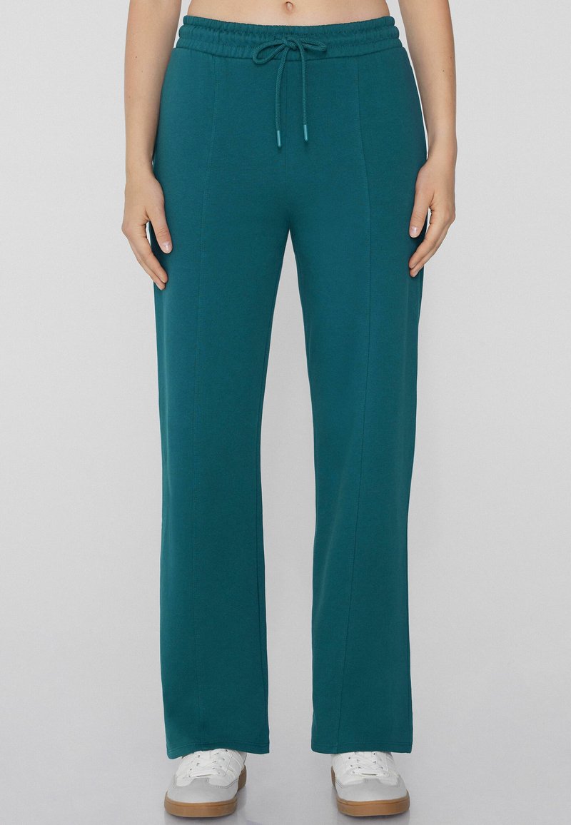 Teal Jogginghosen mit lockerer Passform, elastischem Taillenzug und Kordelzug. Glatte Textur, gerade Beine und Seitennaht für Struktur.