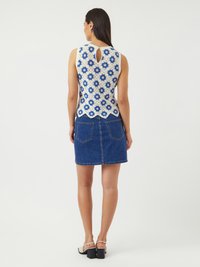 Blonde topp med blå blomstermønster, bølget kant og nøkkelhullsrygg. Kombinert med blå denimskjørt og block-heeled sandaler.