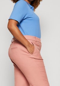 Lichtblauw poloshirt met korte mouwen gecombineerd met roze op maat gemaakte trousers met zakken en een gladde textuur.