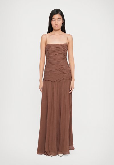 Bruine, vloerlange jurk met spaghetti straps en getextureerde plooien bij het lijfje, overgaand in een soepele, vloeiende rok.