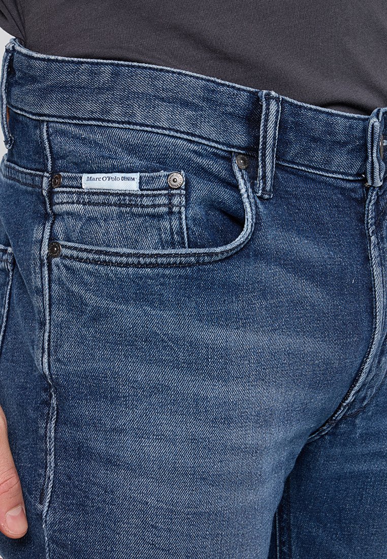 Dunkelblaue Denim-Jeans mit einem klassischen Fünf-Taschen-Design, vorderem Knopf- und Reißverschluss, sowie einem gewebten Markenschild am Bund.
