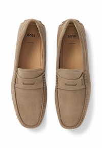 Brune mockasiner i semsket skinn med slip-on design, dekorert med sømdetaljer og en liten logo på overdelen. Laget i Europa.