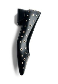 Zapato plano de cuero negro con punta afilada, adornado con ojetes circulares en tono dorado. Tacón bajo y textura suave.