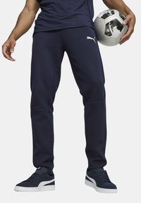 Marina träningsbyxor med slim fit, med elastisk midja, sidfickor och en diskret logodetalj. Kombineras med mörka sneakers.
