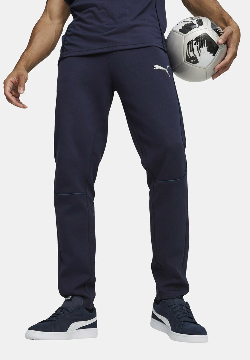 Marineblauwe sportbroek met een slim fit, voorzien van een elastische tailleband, zijzakken en een subtiele logo-detail. Gecombineerd met donkere sneakers.