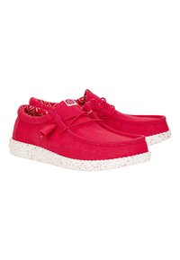 Scarpe di tela rosse con punta tonda, caratterizzate da una suola bianca maculata e un rivestimento interno con motivo. Lacci e una piccola etichetta del logo sul lato.