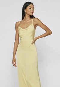 Vestido de satén amarillo con un diseño ajustado, tirantes finos y escote redondo, que presenta una textura suave y brillante.
