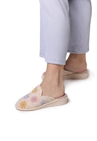 Beige lippulämmittimet, joissa on koristellut moniväriset lumihiutaleet, valmistettu pehmeästä materiaalista, jossa on teksturoitu pinta ja matalaprofiilinen pohja.