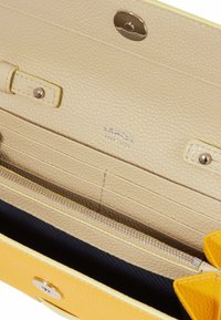 Portefeuille en cuir texturé jaune avec un intérieur beige. Comprend plusieurs emplacements pour cartes, une poche zippée et un accent de nœud décoratif.