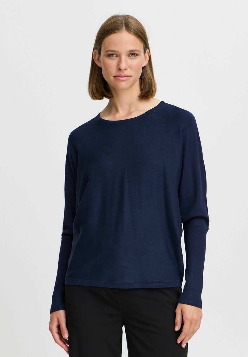 Chemise à manches longues bleu marine en tissu léger avec un col rond et une coupe décontractée. Présente des poignets ajustés et une texture lisse.