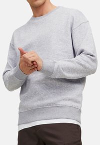 Sweat à col ras du cou gris en polaire avec des poignets et un ourlet côtelés. Présente une coupe décontractée et une texture douce.