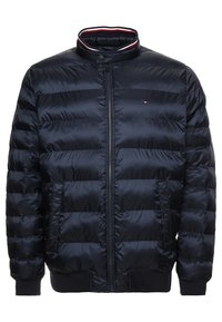 Granatowa kurtka puchowa z pikowanym wzorem, wysoki kołnierz, zamek błyskawiczny z przodu, kieszenie boczne i ściągacze na mankietach. Posiada logo na klatce piersiowej.