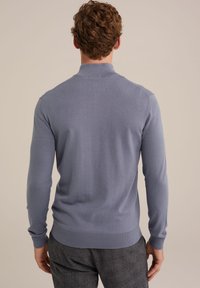 Suéter azul claro con un diseño ajustado, mangas largas y puños acanalados. Textura suave y un cuello clásico en la parte posterior.