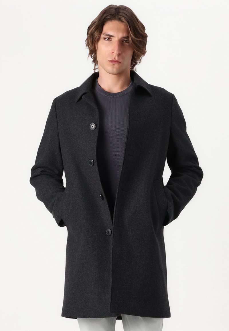 Dunkelgrauer Wollmantel mit Kragen, vorderem Knopfverschluss und seitlichen Taschen. Glatte Textur und taillierte Passform, knielanges Design.