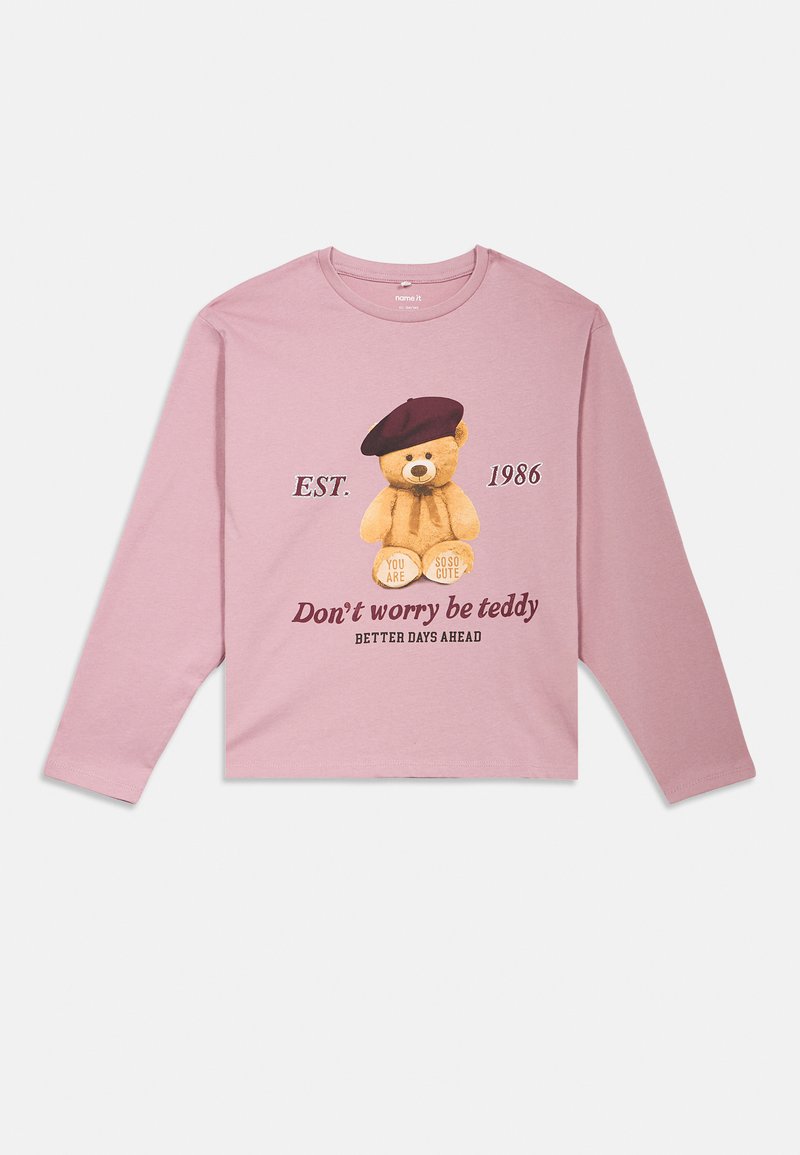 T-shirt de manga longa rosa com um gráfico de um urso de pelúcia a usar uma boina, com texto que inclui "Não te preocupes, sê urso" e "EST. 1986."