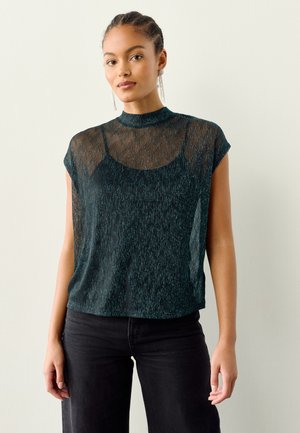 Top de manga corta en color verde azulado oscuro con cuello alto y textura transparente, superpuesto sobre una base simple. Presenta un patrón de rayas sutil.