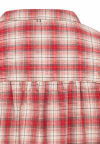 Chemise à carreaux rouge et blanche avec un dos plissé, une fermeture à boutons, et un tissu doux et texturé.