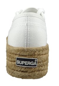 Hvide lærreds sneakers med en tyk jute platformsål, udstyret med et sort og hvidt logo-patch på siden og detaljeret syning på overdelen.