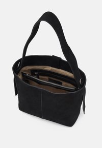 Sac à main en daim noir avec une large bandoulière, intérieur en tissu beige et plusieurs compartiments zippés visibles à l'intérieur.