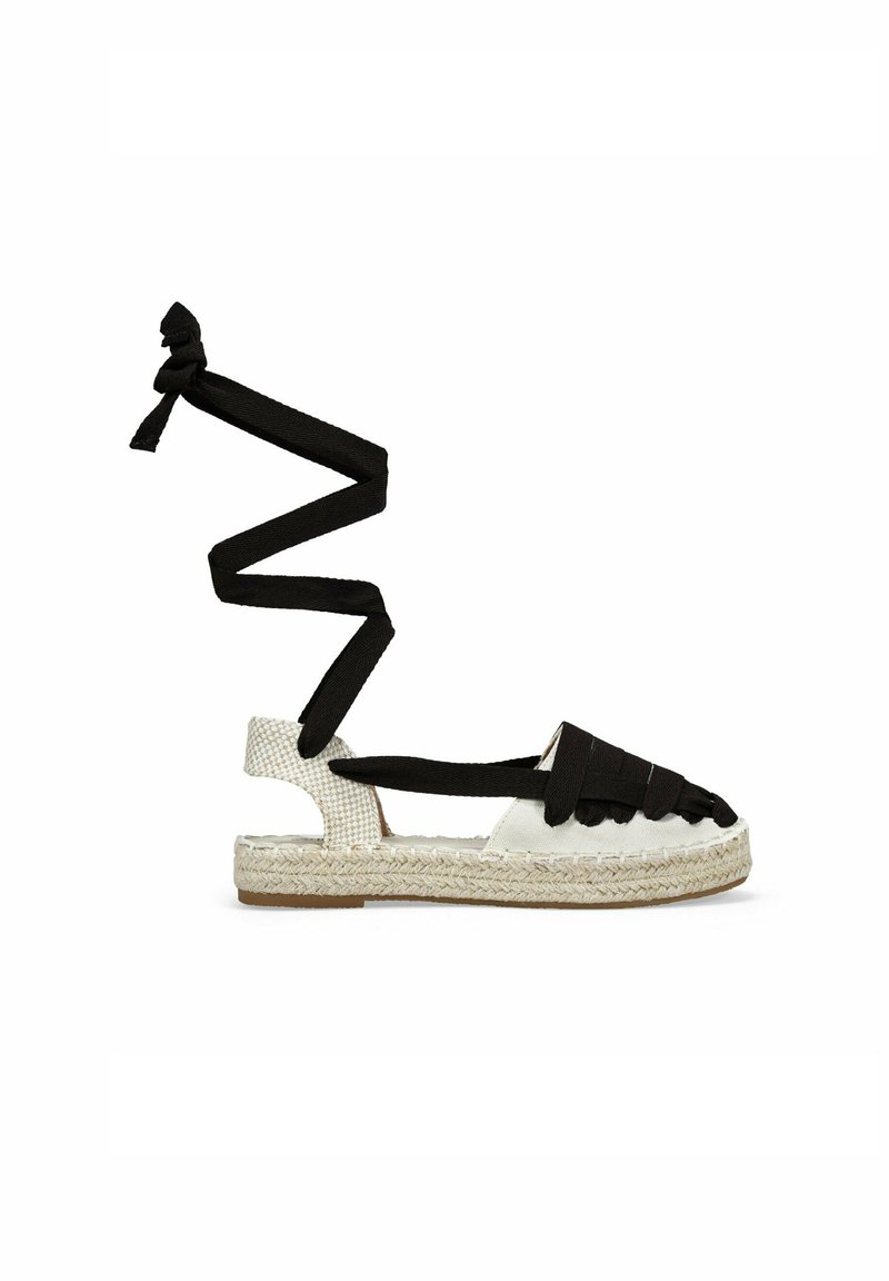Sandalo espadrille con suola in juta intrecciata e tomaia in tela bianca, dotato di cinturini in tessuto nero che si avvolgono per assicurarsi attorno alla caviglia.