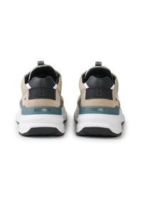 Herresneakers i beige og grå ruskind med sorte accenter og en turkis detalje på hælen. Tykt hvidt sål med en struktureret sort ydersål.