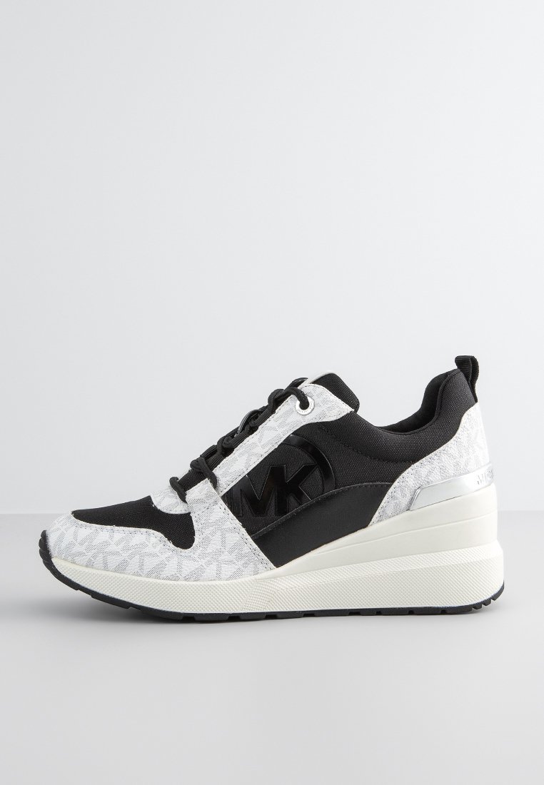 Baskets noires et blanches avec un motif géométrique, partie supérieure en tissu, semelle en caoutchouc robuste et accent argenté au talon. Présente le logo MK bien en vue.