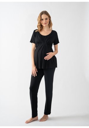 Black maternity top with short sleeves and a gathered waistband, paired with black fitted pants, both in soft, stretchable fabric.