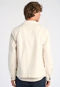 Ljusbeige, långärmad jacka med avslappnad passform, mjukt material, knappmanchetter, ryggsyd och minimalistisk design, perfekt för lager-på-lager.