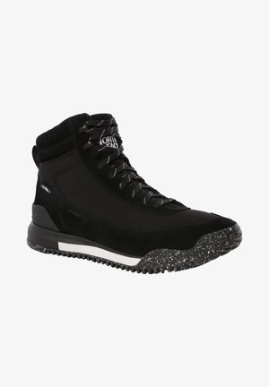 Bottes de randonnée noires avec une tige en suède texturé et tissu. Elles présentent une semelle tachetée, une bande blanche contrastante et des lacets noirs.