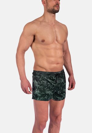 Shorts de bain camouflés verts en matériau léger et brillant. Dotés d'une taille élastique avec cordon de serrage et de poches latérales.