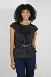 Top en satin noir avec des manches courtes, design plissé et taille ceinturée avec une boucle dorée, associé à un jean bleu foncé.