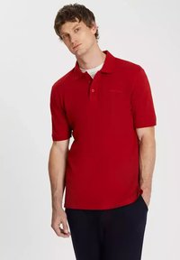 Czerwona koszulka polo z krótkim rękawem, z kołnierzykiem, z zapięciem na trzy guziki oraz subtelnym logo. Wykonana z gładkiej tkaniny w klasycznym kroju.