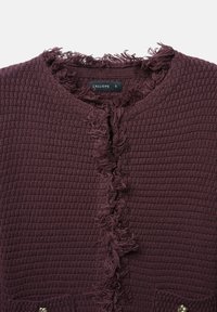 Burgunderfarbene strukturierte Strickjacke mit fransigen Kanten, Knopfschluss und gewebtem Muster. Verfügt über ein Etikett mit dem Markennamen "Calliope."
