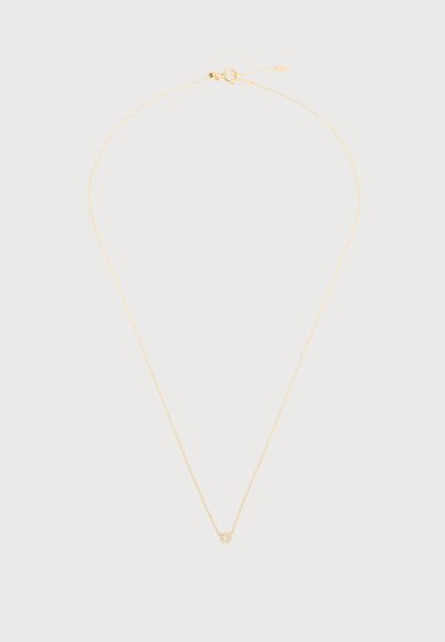 Λεπτό κολιέ με χρυσή αλυσίδα και μικρό, στρογγυλό, υφασμένο μενταγιόν με κούμπωμα δακτυλίου ελατηρίου σε ανοιχτό φόντο.