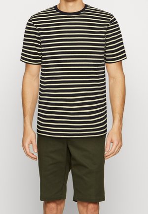 T-shirt rayé noir et jaune pâle, en tissu doux, avec col rond, manches courtes, coupe décontractée, associé à un short vert olive.