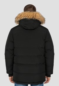 Sort dunjakke med hætte med pelskant, der har en firkantet silhuet, ribstrikkede ærmeafslutninger og syninger på kroppen.