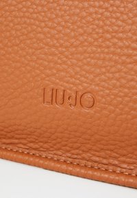 Portafoglio in pelle Liu Jo di colore arancione testurizzato con logo impresso e bordi cuciti, che mette in evidenza un materiale morbido e una costruzione durevole.