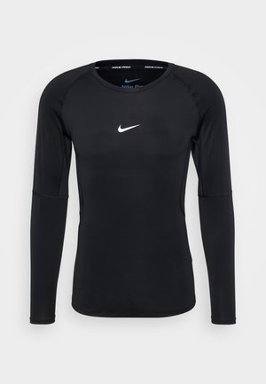 Maglietta da allenamento nera a maniche lunghe realizzata in materiale elasticizzato. Presenta un collo rotondo e un piccolo logo Nike bianco sul petto. Texture liscia.