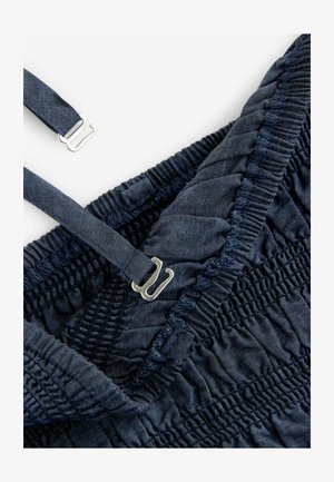 Tessuto blu navy con texture arricciata, dotato di spalline regolabili e accessori metallici per la chiusura. Dettagliato con cuciture elastiche.