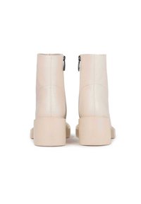 Bottes chelsea créme en cuir lisse, dotées d'un talon bloc et de détails zippés sur les côtés pour un enfilage facile.