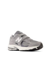 Chaussure de sport grise avec un dessus en mesh et en suède, sangle ajustable, col rembourré et semelle extérieure en caoutchouc texturé avec une unité d'air visible.